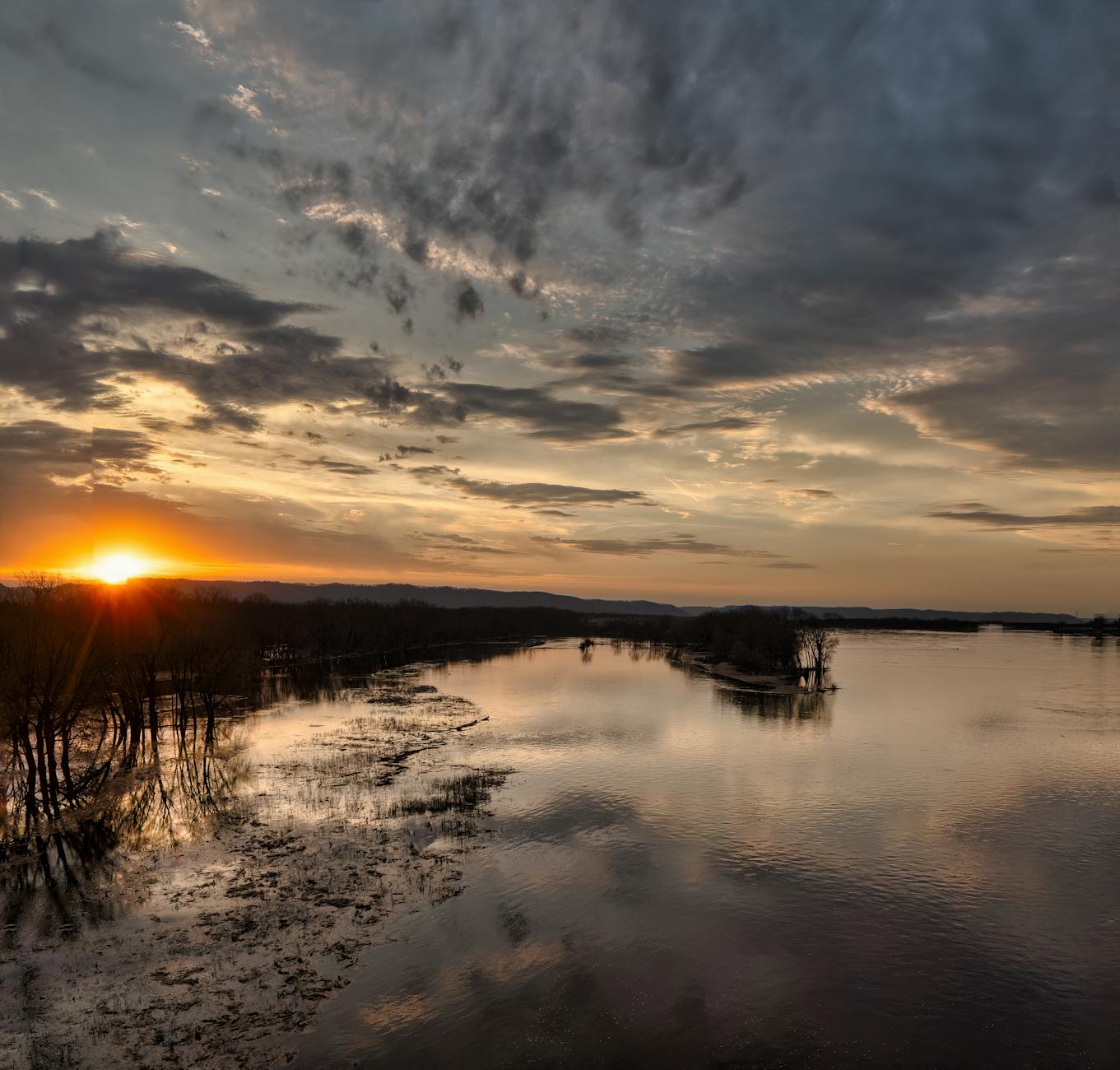 Zachód słońca nad rzeką z kolorowymi chmurami na tle horyzontu