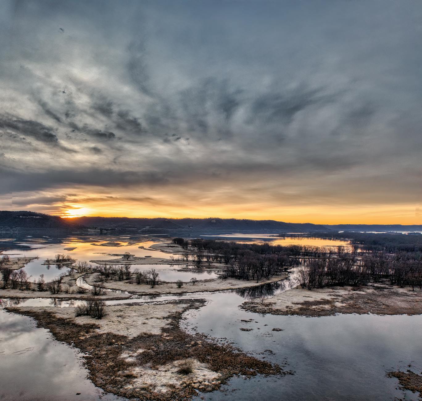 Zachód słońca nad szeroką rzeką z dramatycznymi chmurami na niebie